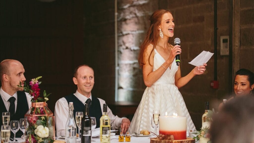 Woman giving toast at wedding celebration